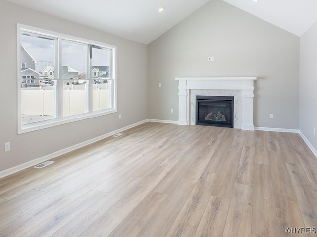 unfurnished living room featuring vaulted ceiling, a wealth of natural light, and a high end fireplace