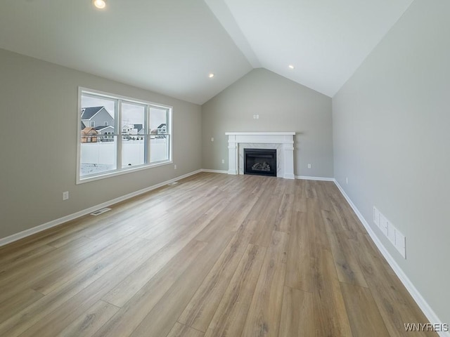 unfurnished living room with lofted ceiling, light wood-type flooring, and a fireplace