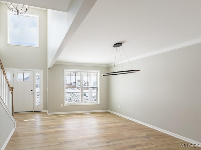 foyer with crown molding, light hardwood / wood-style floors, and a notable chandelier