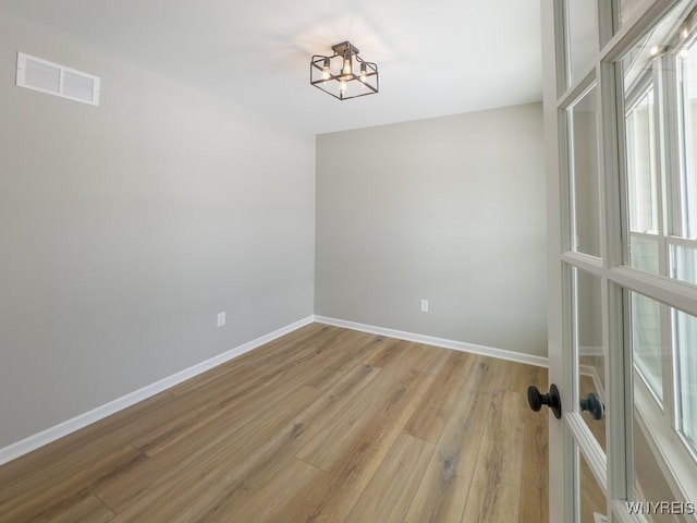 spare room with a notable chandelier and light hardwood / wood-style floors