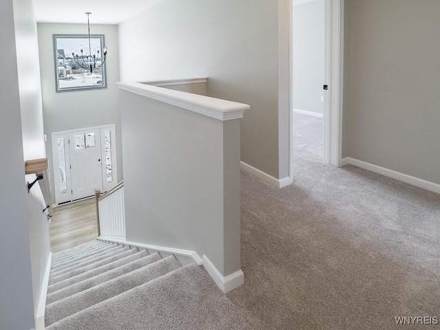 stairway with carpet floors and a chandelier