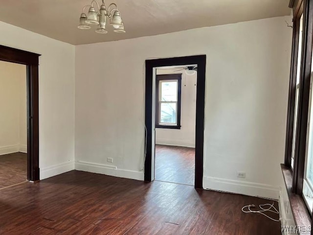 unfurnished room featuring ceiling fan with notable chandelier and dark hardwood / wood-style floors