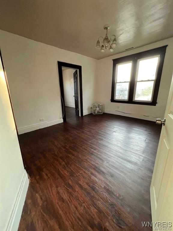 unfurnished room with dark hardwood / wood-style flooring and an inviting chandelier