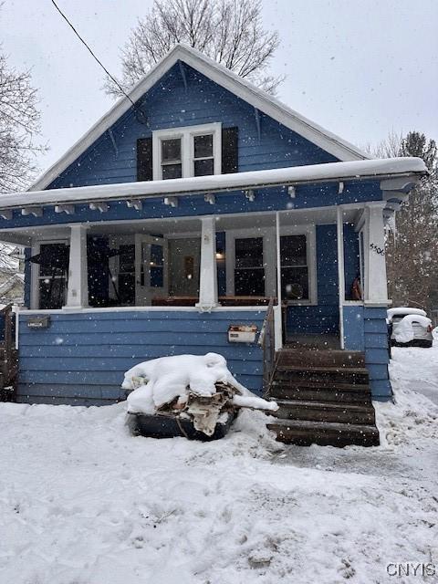 snow covered back of property featuring a porch