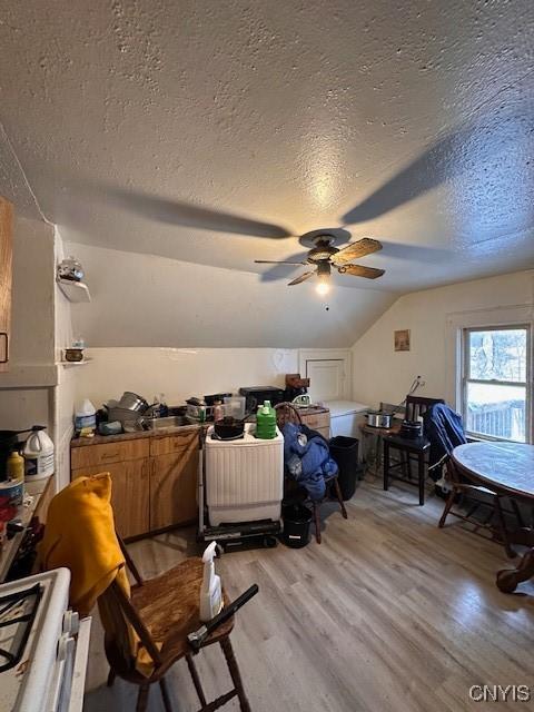 bonus room featuring vaulted ceiling, a textured ceiling, a ceiling fan, and light wood-style floors