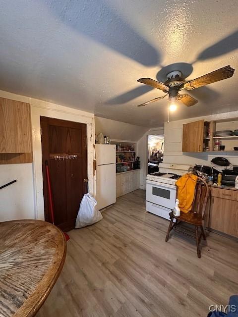 kitchen with a textured ceiling, white appliances, vaulted ceiling, ceiling fan, and light hardwood / wood-style floors