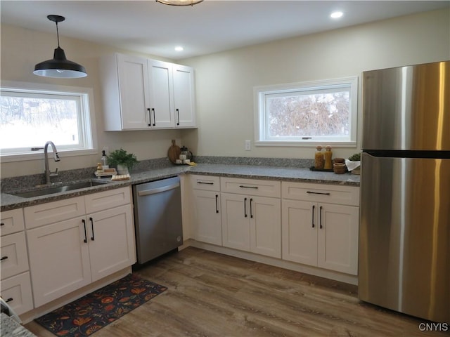 kitchen featuring dark wood-type flooring, sink, dark stone countertops, appliances with stainless steel finishes, and white cabinetry