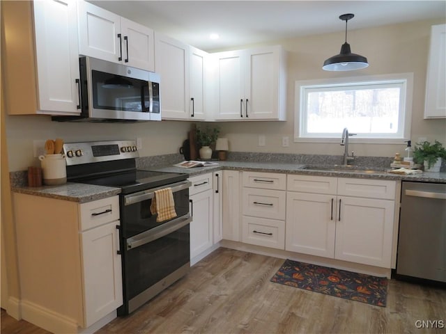 kitchen featuring white cabinets, sink, stainless steel appliances, and light hardwood / wood-style flooring