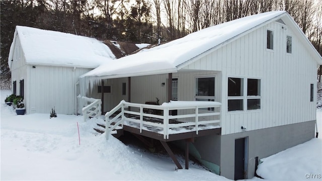 snow covered rear of property featuring a deck