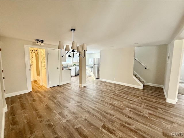 unfurnished living room with wood-type flooring and a notable chandelier