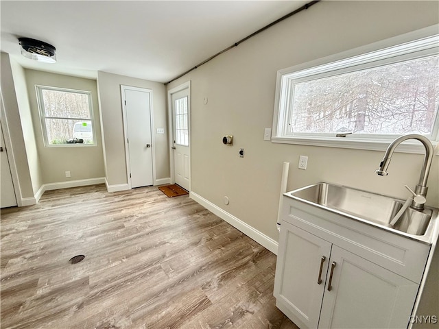 interior space with cabinets, light hardwood / wood-style flooring, electric dryer hookup, and sink