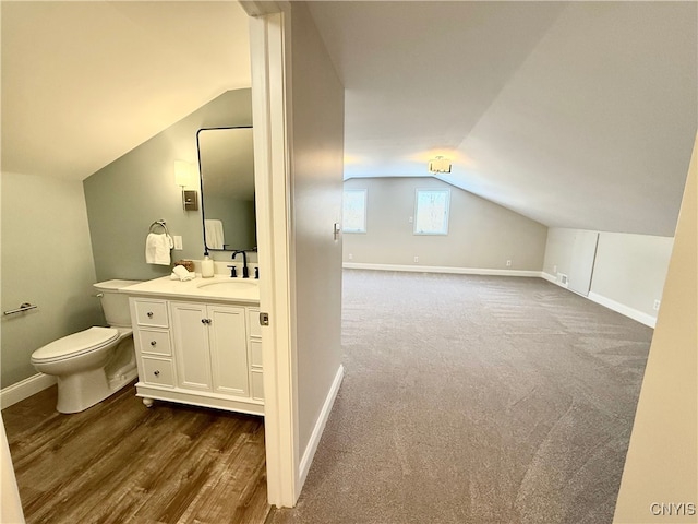 bathroom featuring vanity, wood-type flooring, lofted ceiling, and toilet