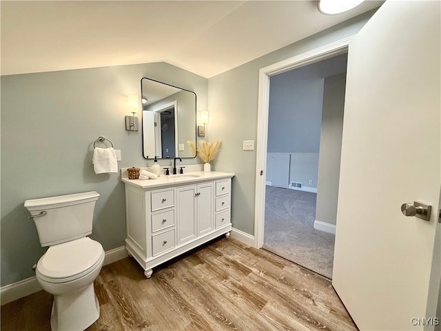 bathroom with vanity, wood-type flooring, vaulted ceiling, and toilet