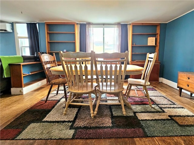 dining room featuring a wall mounted air conditioner and wood-type flooring