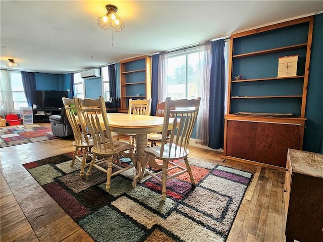 dining space featuring hardwood / wood-style floors and a wall unit AC