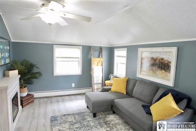 living room featuring ceiling fan, light hardwood / wood-style flooring, a baseboard heating unit, vaulted ceiling, and a fireplace