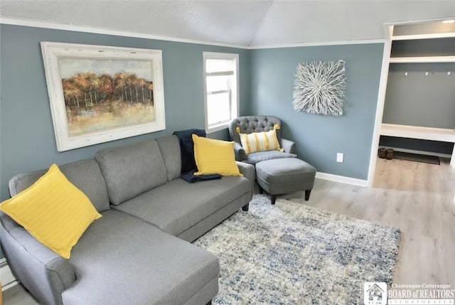 living room with light hardwood / wood-style floors, lofted ceiling, and ornamental molding