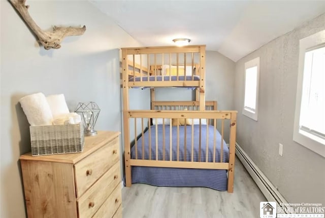 bedroom featuring light wood-type flooring, lofted ceiling, and baseboard heating