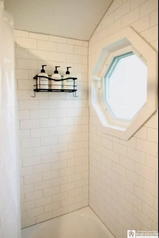 bathroom with vaulted ceiling and shower / tub combo