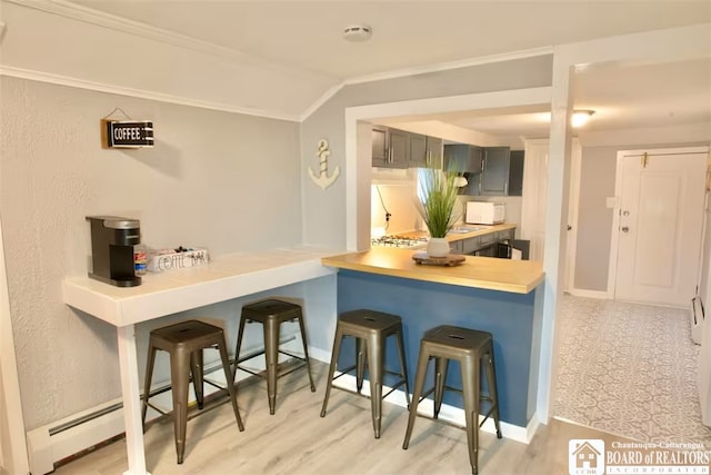 kitchen featuring gray cabinets, a kitchen bar, lofted ceiling, and kitchen peninsula