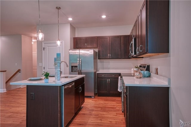 kitchen featuring pendant lighting, a center island with sink, sink, light hardwood / wood-style floors, and stainless steel appliances