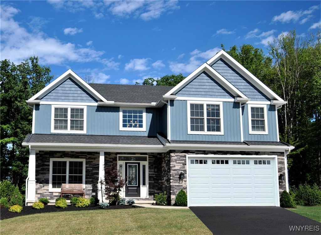 craftsman-style home featuring covered porch, a front lawn, and a garage