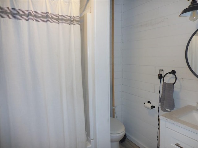 bathroom with vanity, toilet, walk in shower, and wooden walls