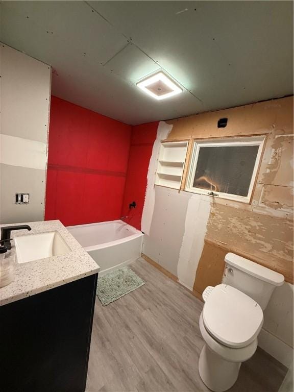 bathroom with a tub, hardwood / wood-style floors, vanity, and toilet