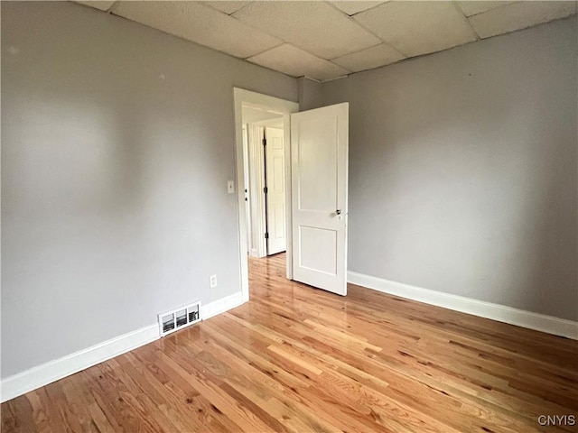 unfurnished room featuring light wood-type flooring and a paneled ceiling