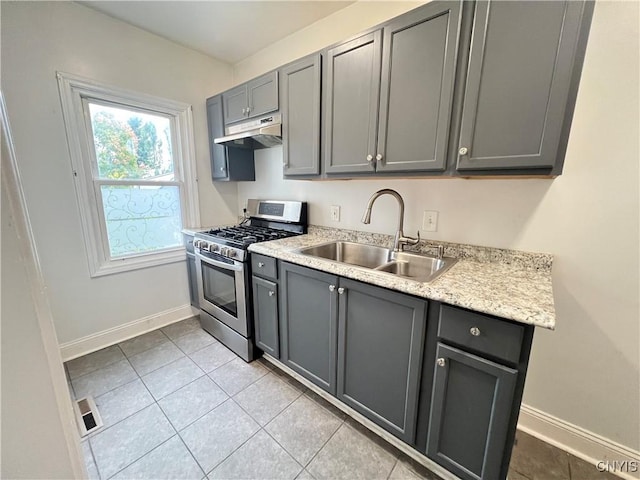 kitchen featuring light tile patterned floors, stainless steel gas range oven, gray cabinetry, and sink