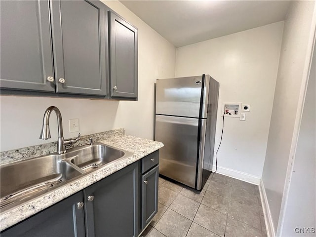 kitchen featuring gray cabinetry, stainless steel fridge, light tile patterned floors, and sink