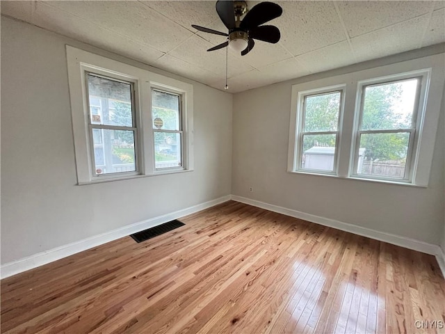 unfurnished room with a paneled ceiling, ceiling fan, and light wood-type flooring