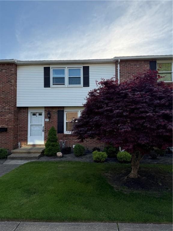 view of front of property with a front lawn and brick siding