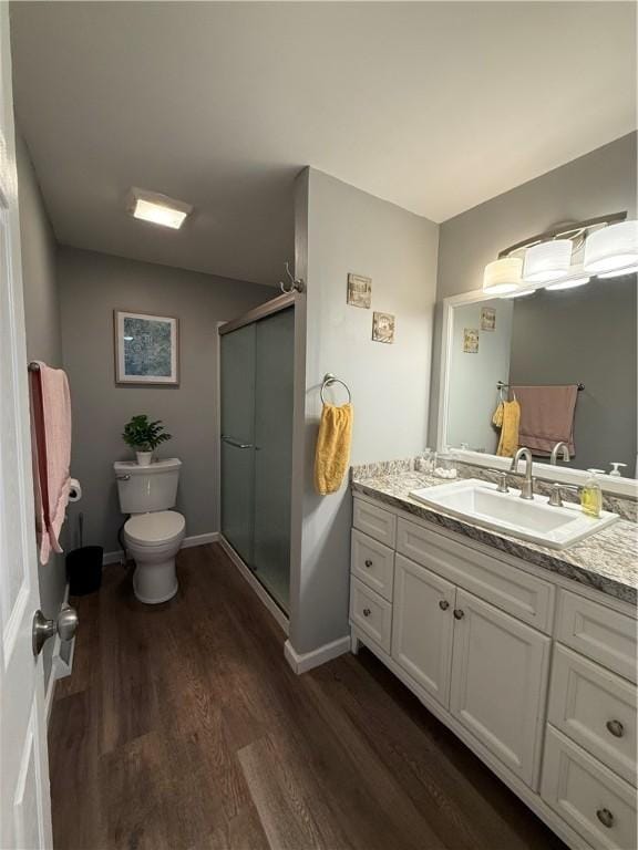 full bathroom with wood finished floors, toilet, a stall shower, vanity, and baseboards