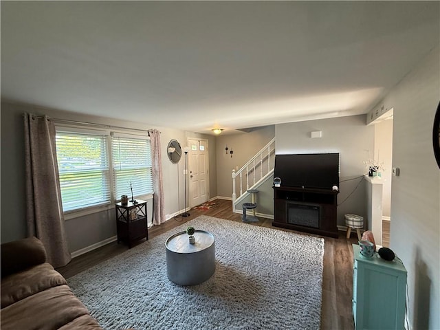 living area with wood finished floors, stairway, and baseboards