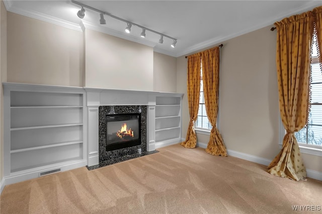 unfurnished living room featuring carpet flooring, built in shelves, and ornamental molding