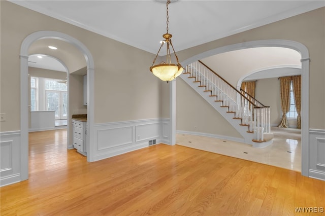 unfurnished dining area featuring light hardwood / wood-style floors and ornamental molding