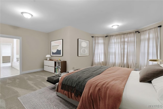 bedroom featuring light colored carpet and ensuite bath