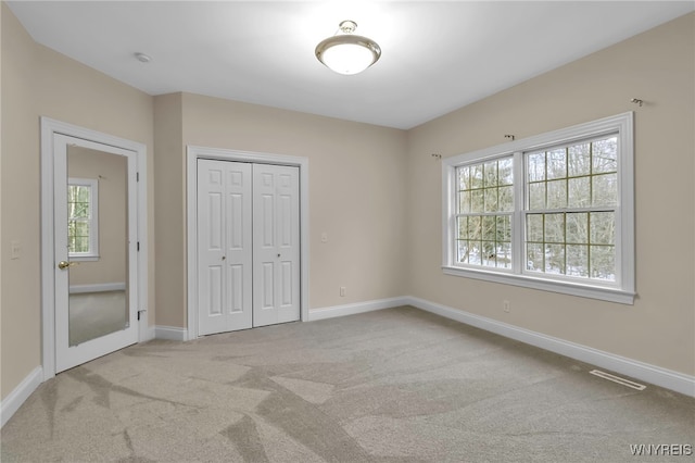 unfurnished bedroom with a closet and light colored carpet