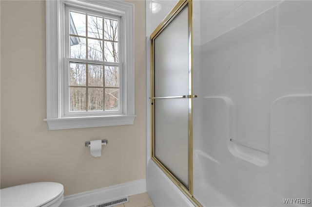 bathroom with toilet, tile patterned flooring, and combined bath / shower with glass door