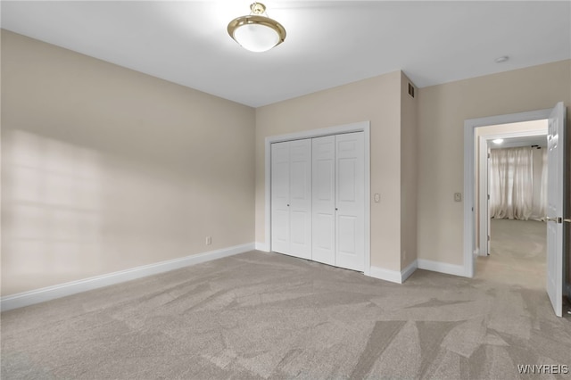 unfurnished bedroom featuring light carpet and a closet