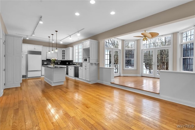 kitchen with white cabinets, paneled fridge, french doors, and pendant lighting