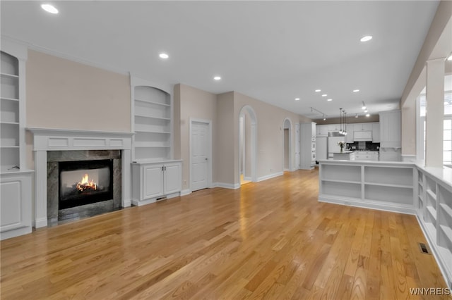 unfurnished living room featuring a fireplace, light hardwood / wood-style flooring, and built in features