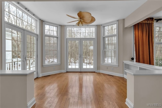 unfurnished sunroom with ceiling fan and french doors