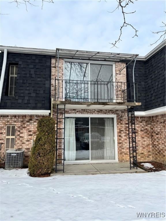 snow covered house featuring a balcony and cooling unit