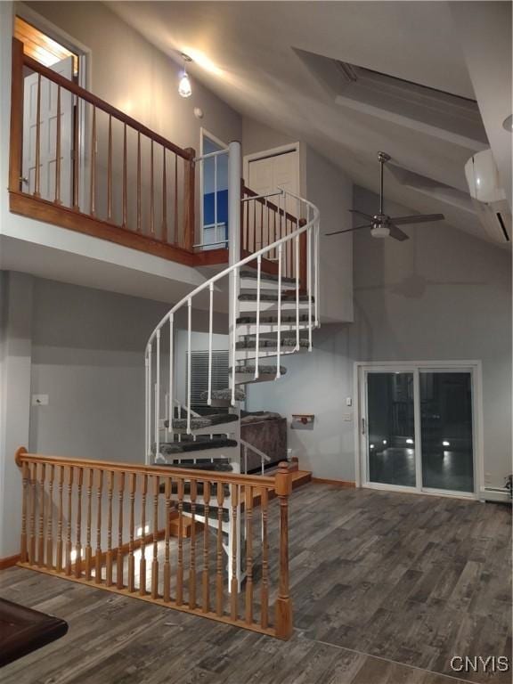 stairway featuring ceiling fan, wood-type flooring, and high vaulted ceiling