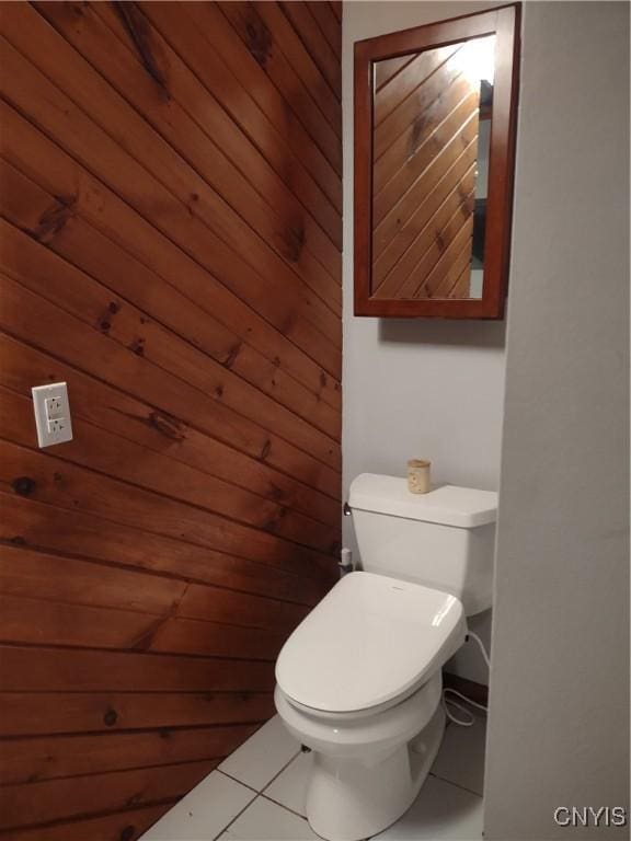 bathroom featuring toilet, tile patterned flooring, and wood walls