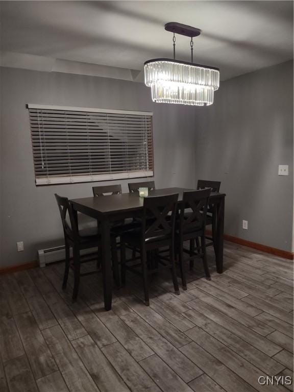 dining space with a baseboard heating unit, a chandelier, and hardwood / wood-style floors