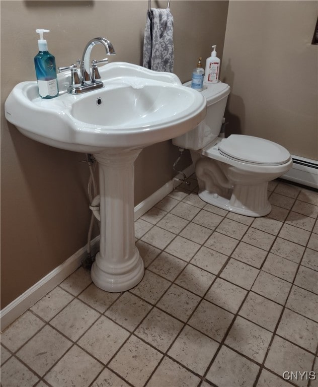 bathroom with a baseboard heating unit, toilet, and tile patterned flooring