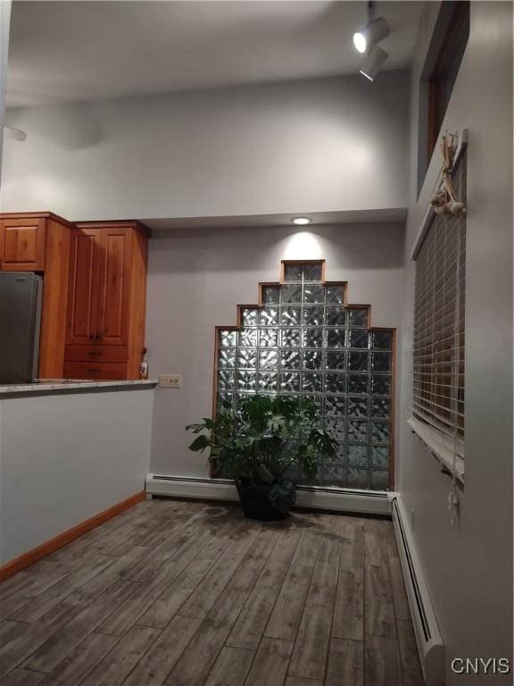 interior space featuring baseboard heating, a towering ceiling, and hardwood / wood-style flooring